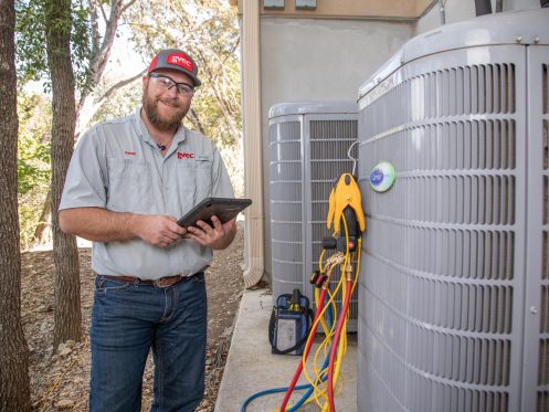 HVAC technician standing by unit